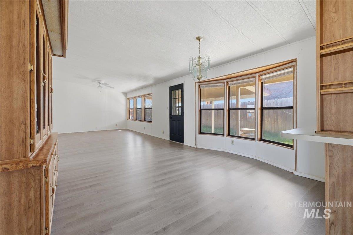 Unfurnished dining area featuring light wood finished floors, suspended lighting, and a textured ceiling