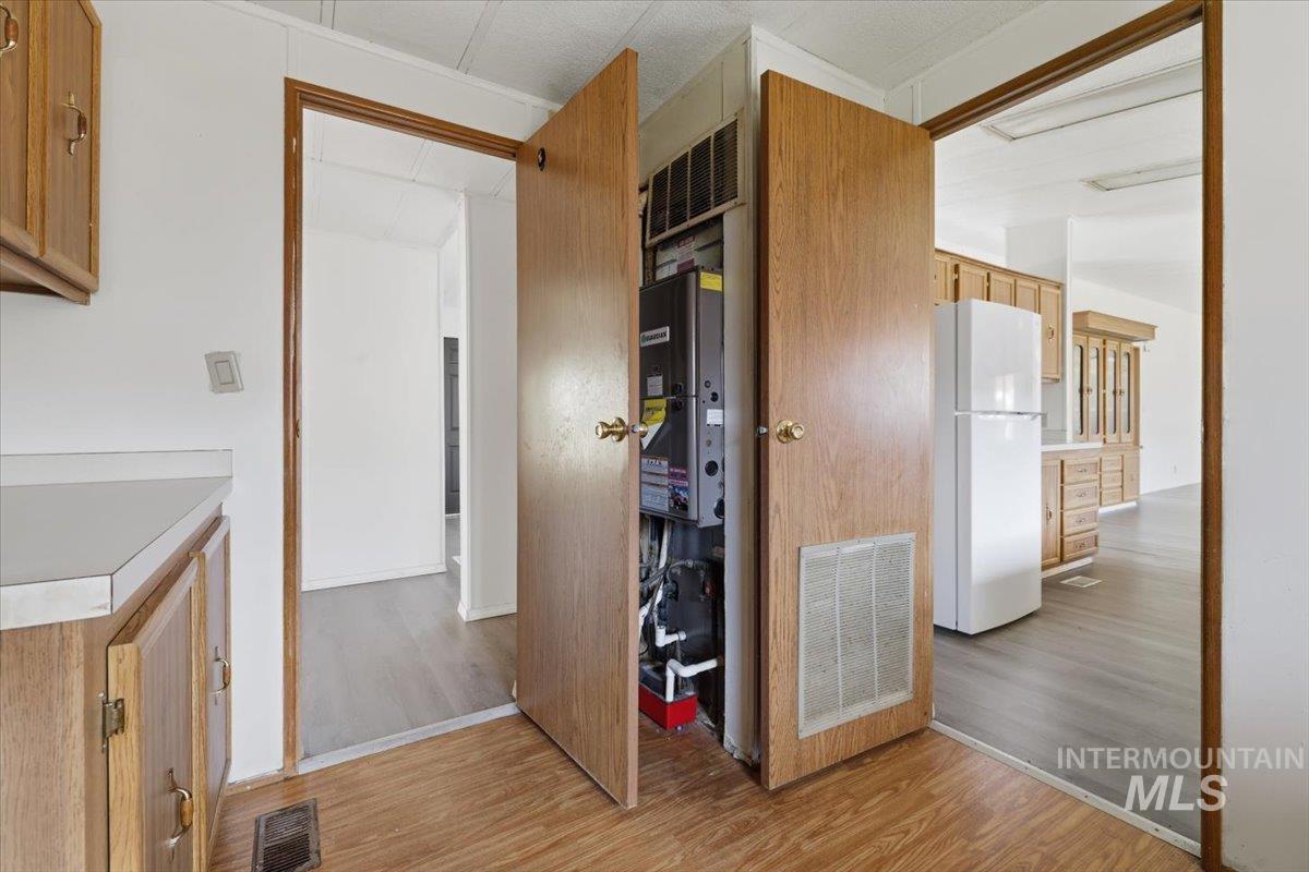 Kitchen featuring light wood-style flooring, freestanding refrigerator, light countertops, light wood finish cabinetry, and wood finish cabinetry