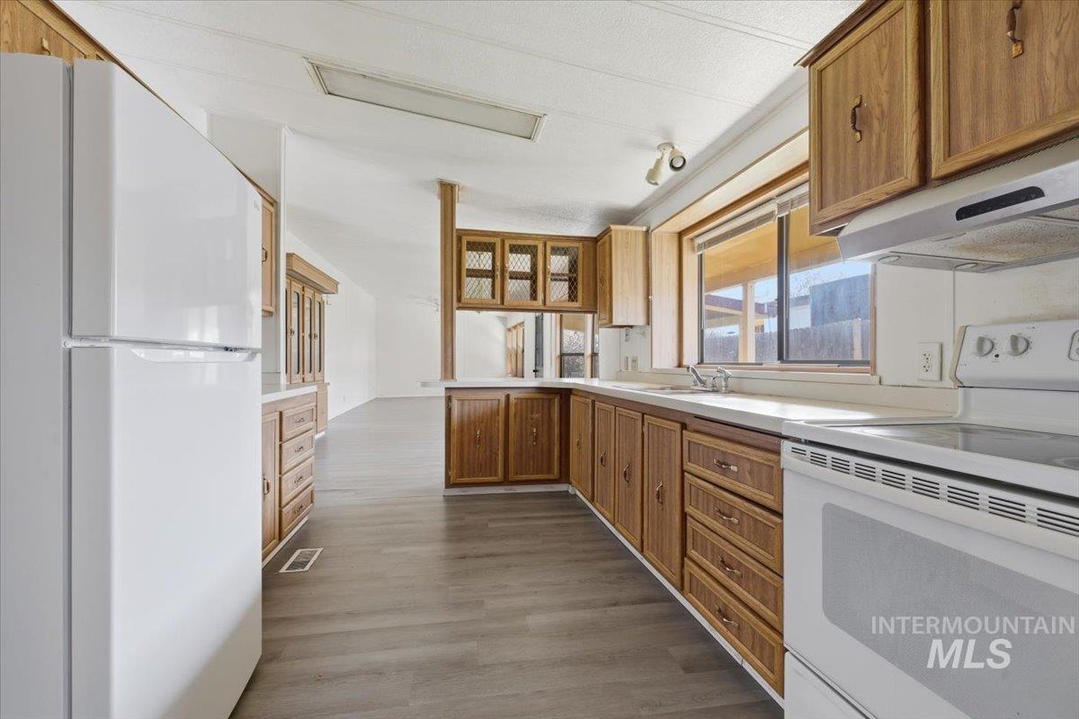 Kitchen featuring white appliances, a peninsula, and wood finish cabinets