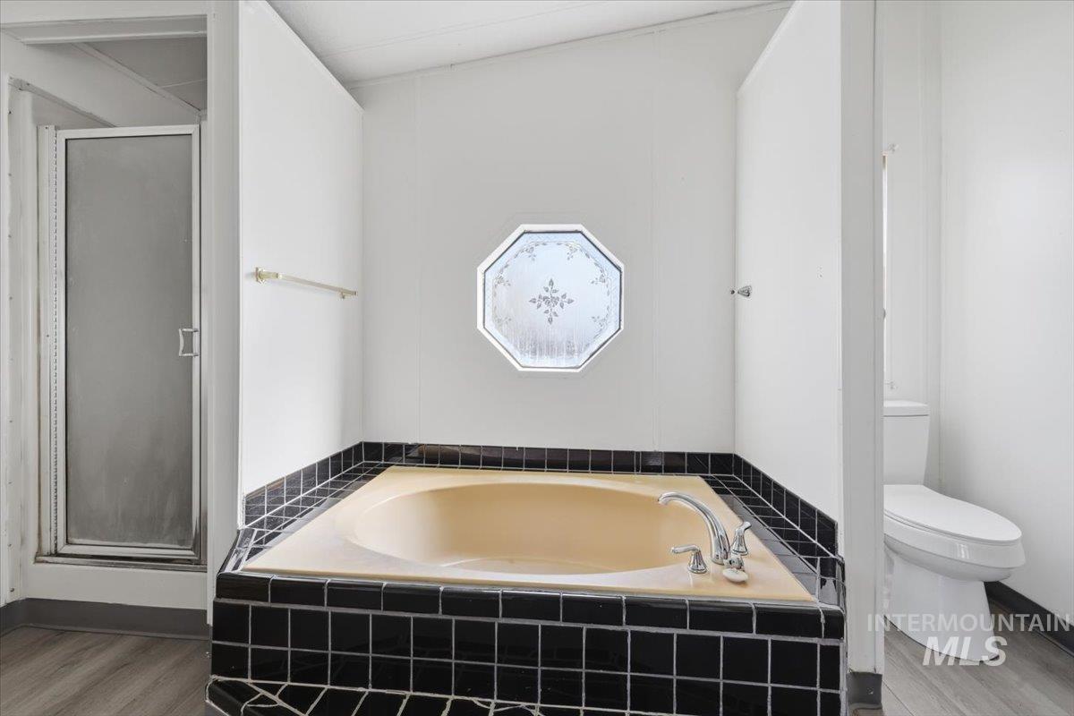 Full bathroom with a bath, a shower stall, and wood finished floors