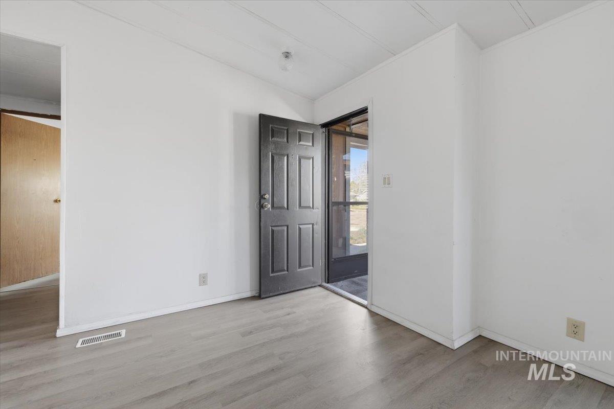 Unfurnished room featuring light wood finished floors and vaulted ceiling