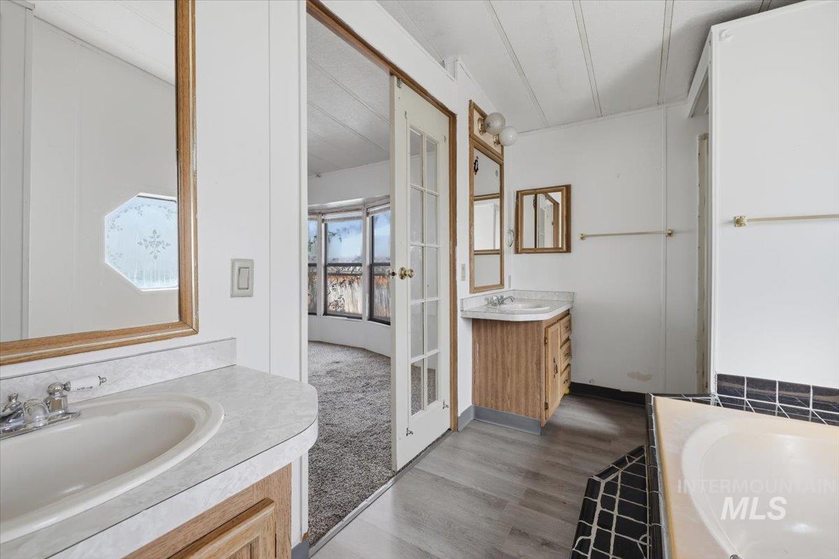 Bathroom with two vanities, a garden tub, and dark wood-style floors