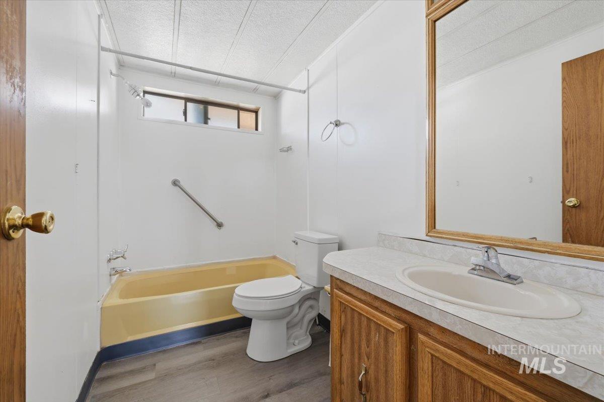 Bathroom with vanity, a textured ceiling, dark wood-type flooring, and shower / washtub combination