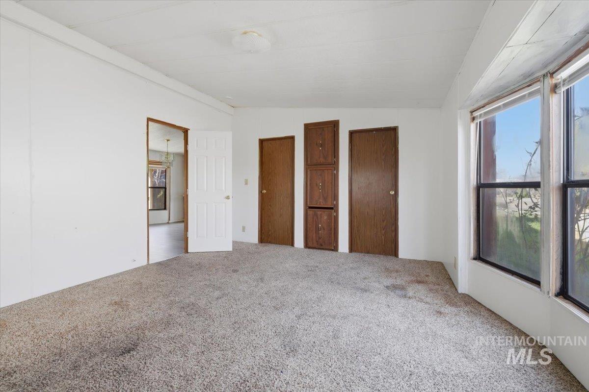 Unfurnished bedroom featuring vaulted ceiling, carpet, and multiple closets