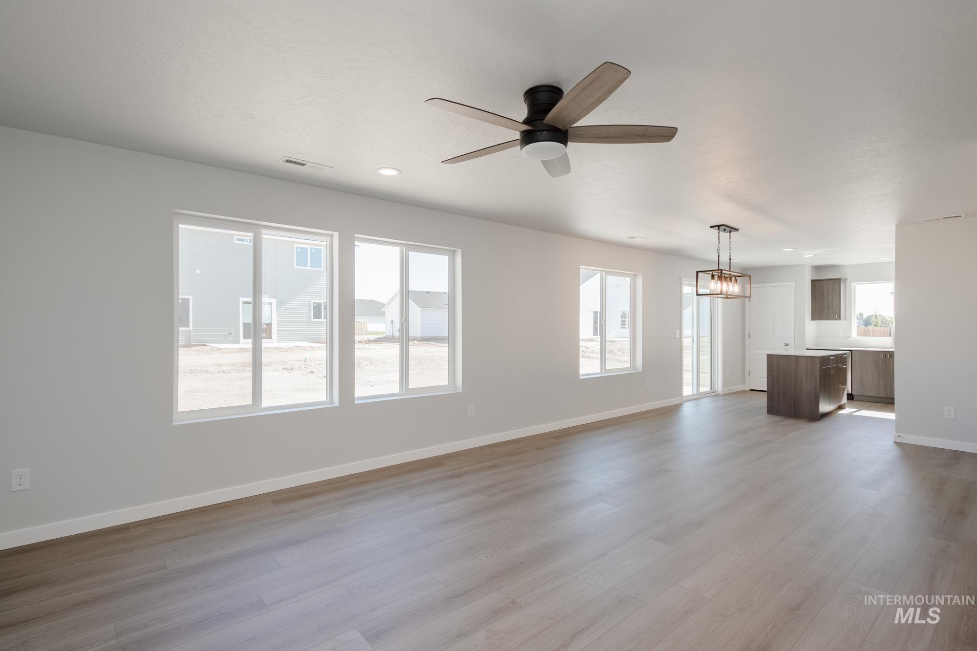 Unfurnished living room with light wood-style floors, a ceiling fan, and a chandelier