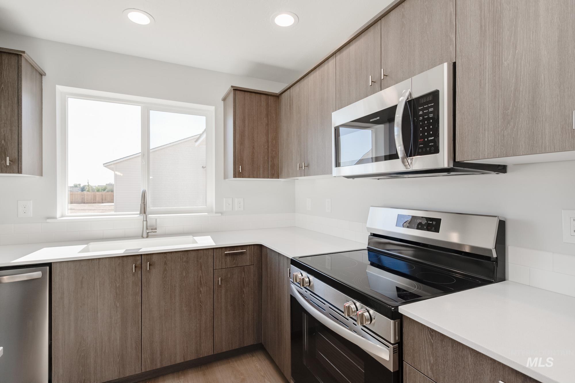 Kitchen with stainless steel appliances, light wood-style floors, modern cabinets, recessed lighting, and light stone countertops