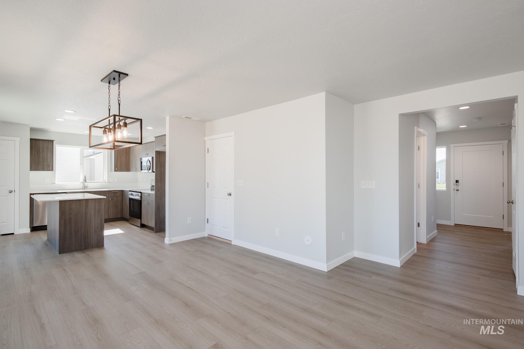 Unfurnished living room featuring light wood-style floors, recessed lighting, and a chandelier