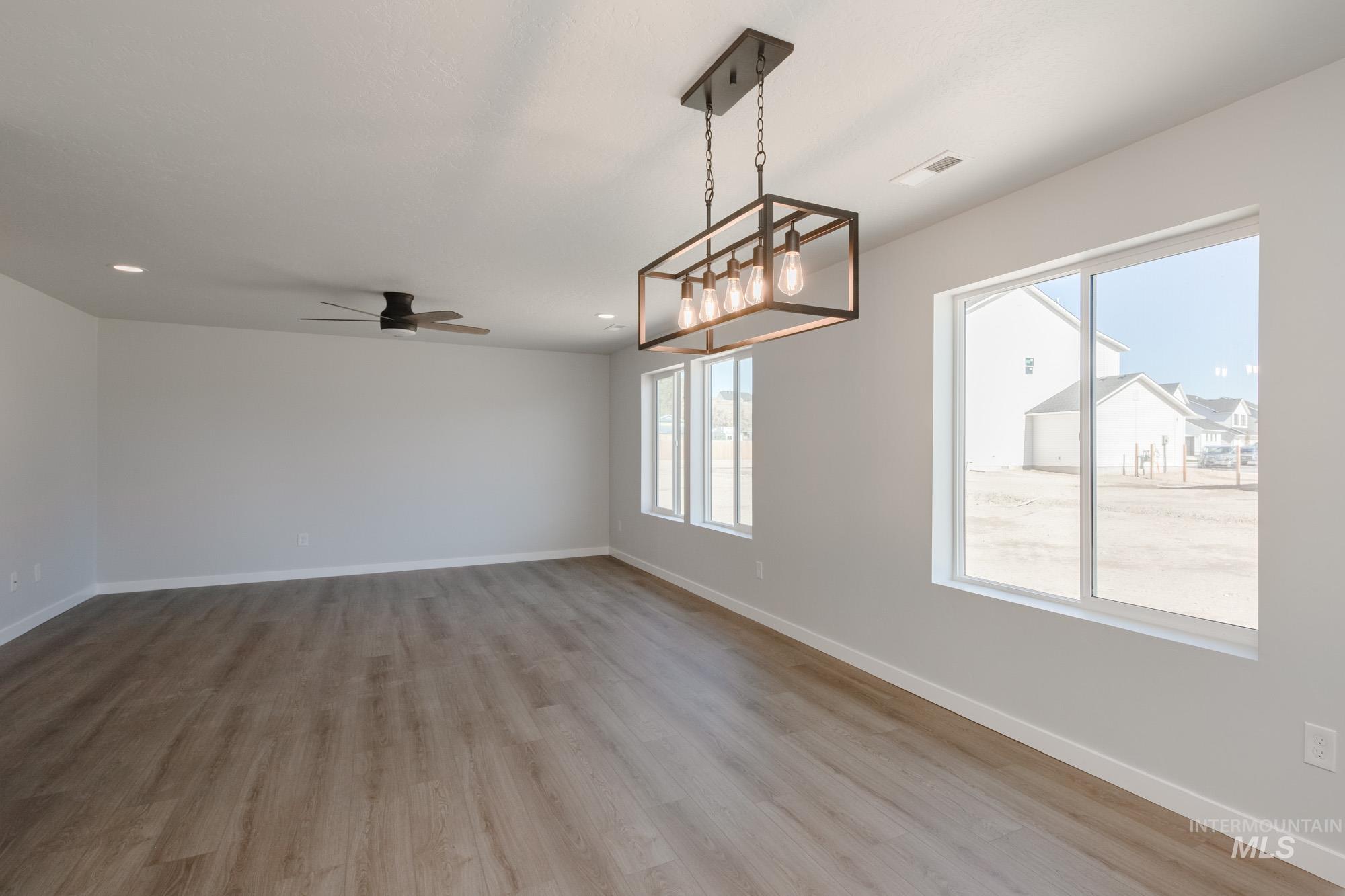 Unfurnished dining area with light wood-style flooring, a chandelier, ceiling fan, and recessed lighting