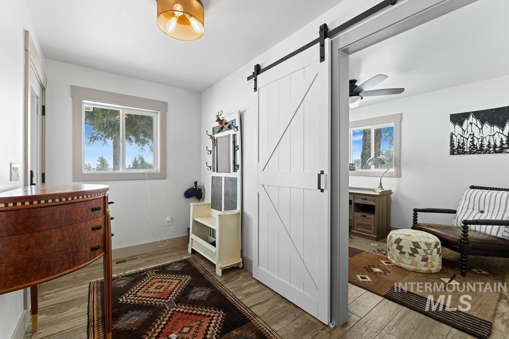 Office space featuring wood finished floors, healthy amount of natural light, a barn door, and ceiling fan