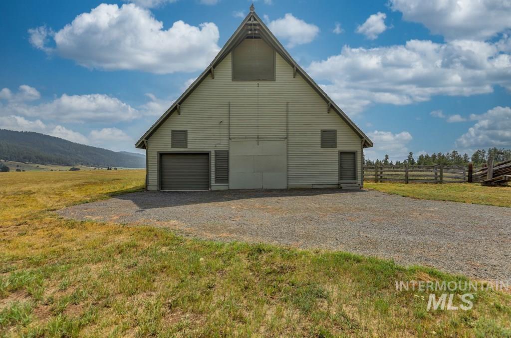 View of side of home featuring an outdoor structure, a barn, a detached garage, and a view of countryside