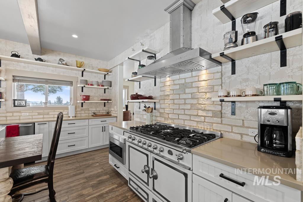 Kitchen featuring open shelves, white cabinets, backsplash, wall chimney range hood, and dark wood-type flooring