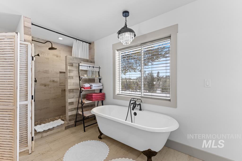 Full bath with a walk in shower, a freestanding bath, a closet, a chandelier, and recessed lighting