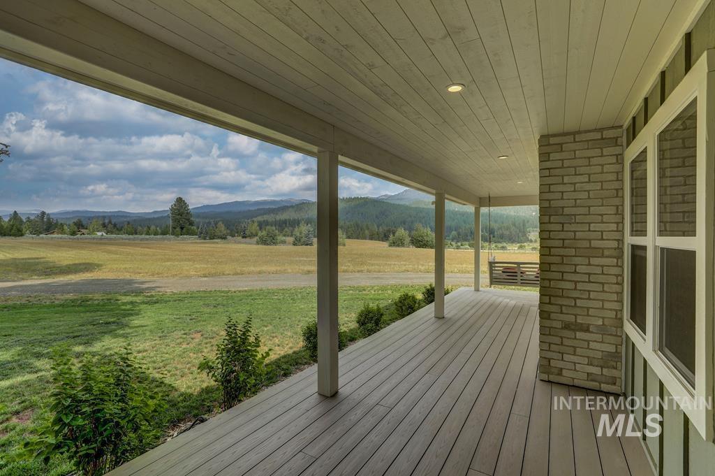 Wooden porch with a mountain view, a yard, and a view of rural / pastoral area