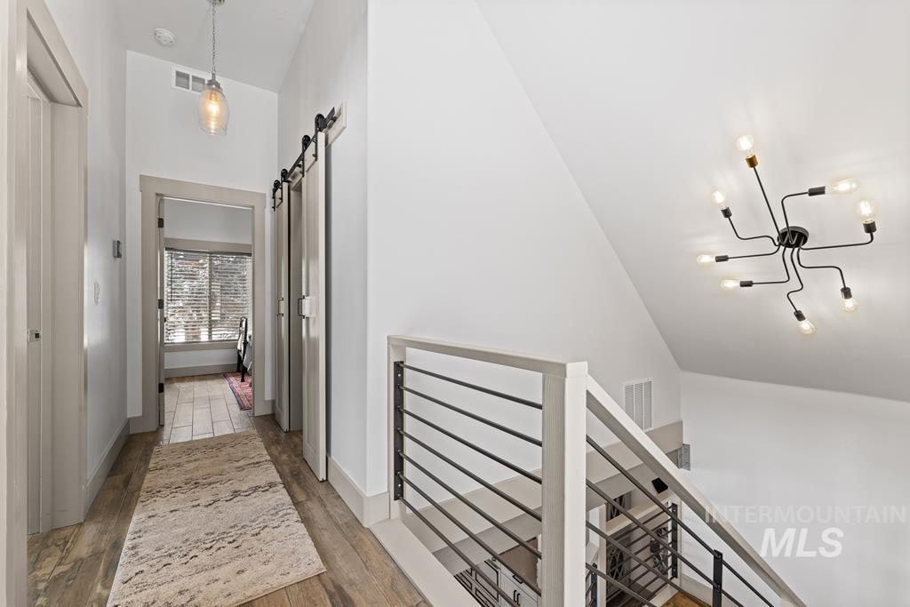Hall featuring a barn door, dark wood-type flooring, and an upstairs landing