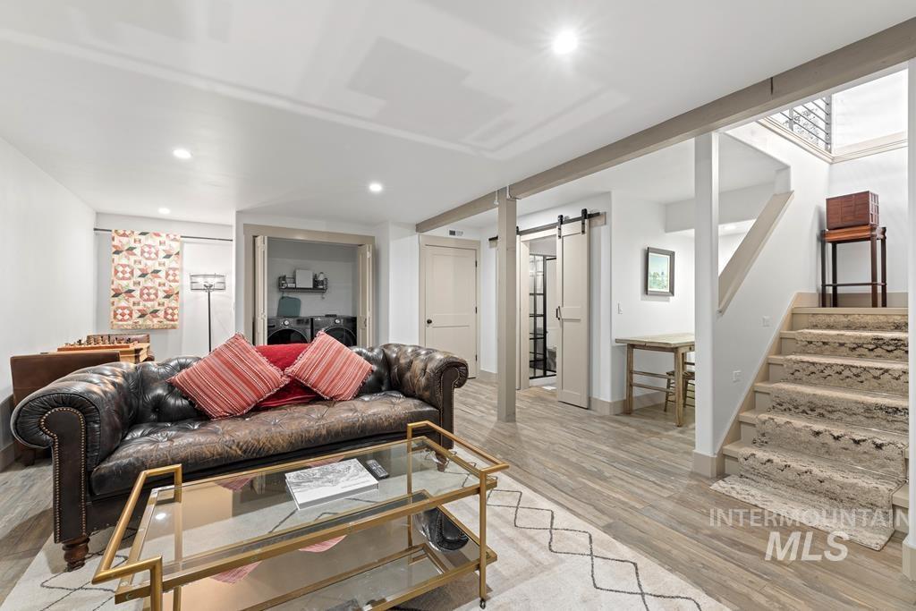 Living area featuring a barn door, stairs, light wood-type flooring, recessed lighting, and washing machine and dryer