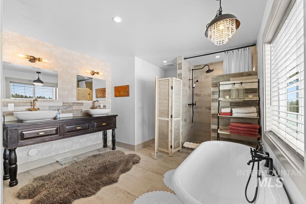 Bathroom with a freestanding bath, a walk in shower, double vanity, tasteful backsplash, and light wood-type flooring