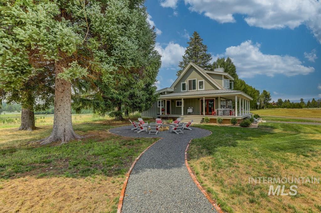 Farmhouse with a porch, a front lawn, a chimney, and board and batten siding