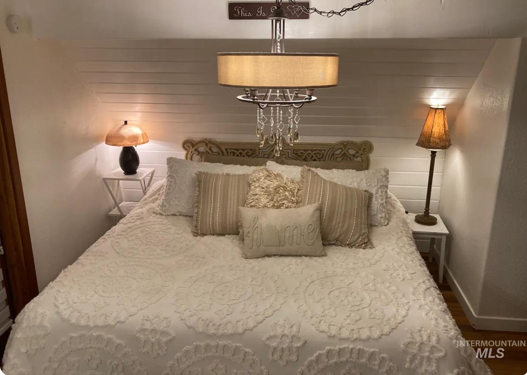 Bedroom with dark wood-style flooring and wooden walls