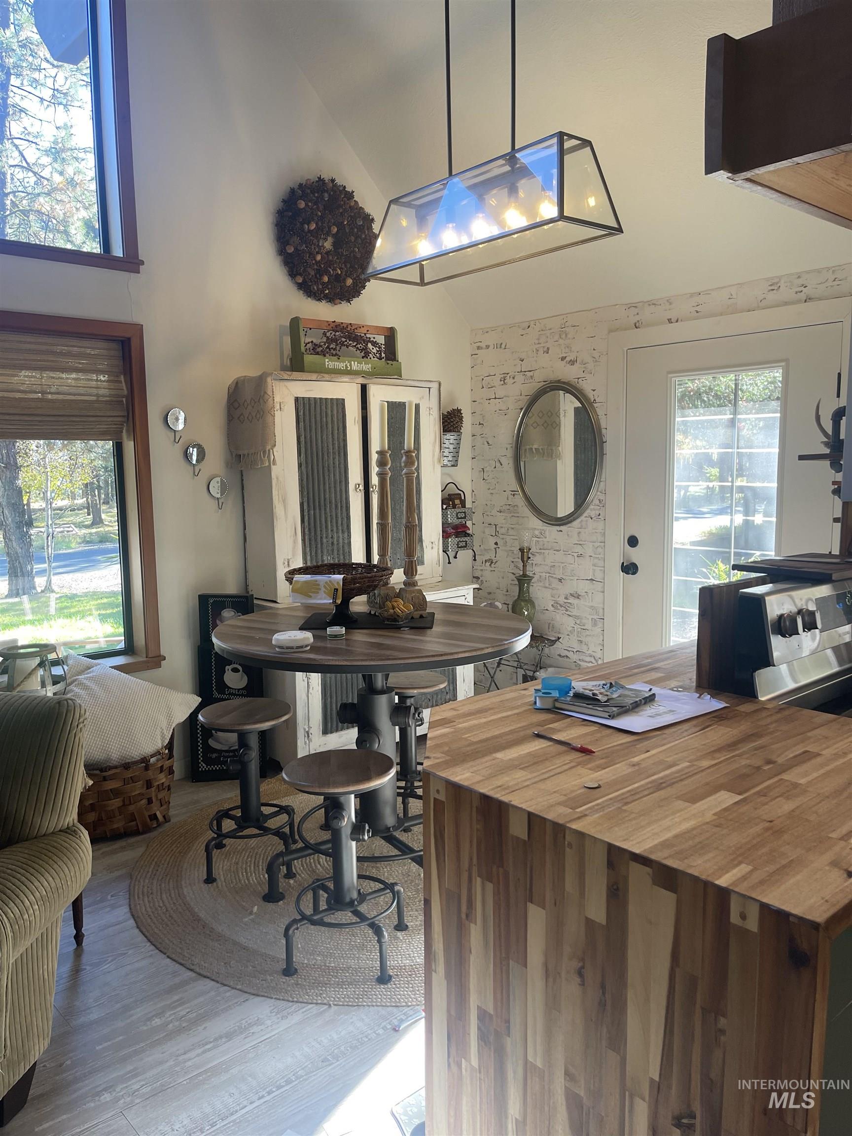 Dining area with high vaulted ceiling and light wood finished floors