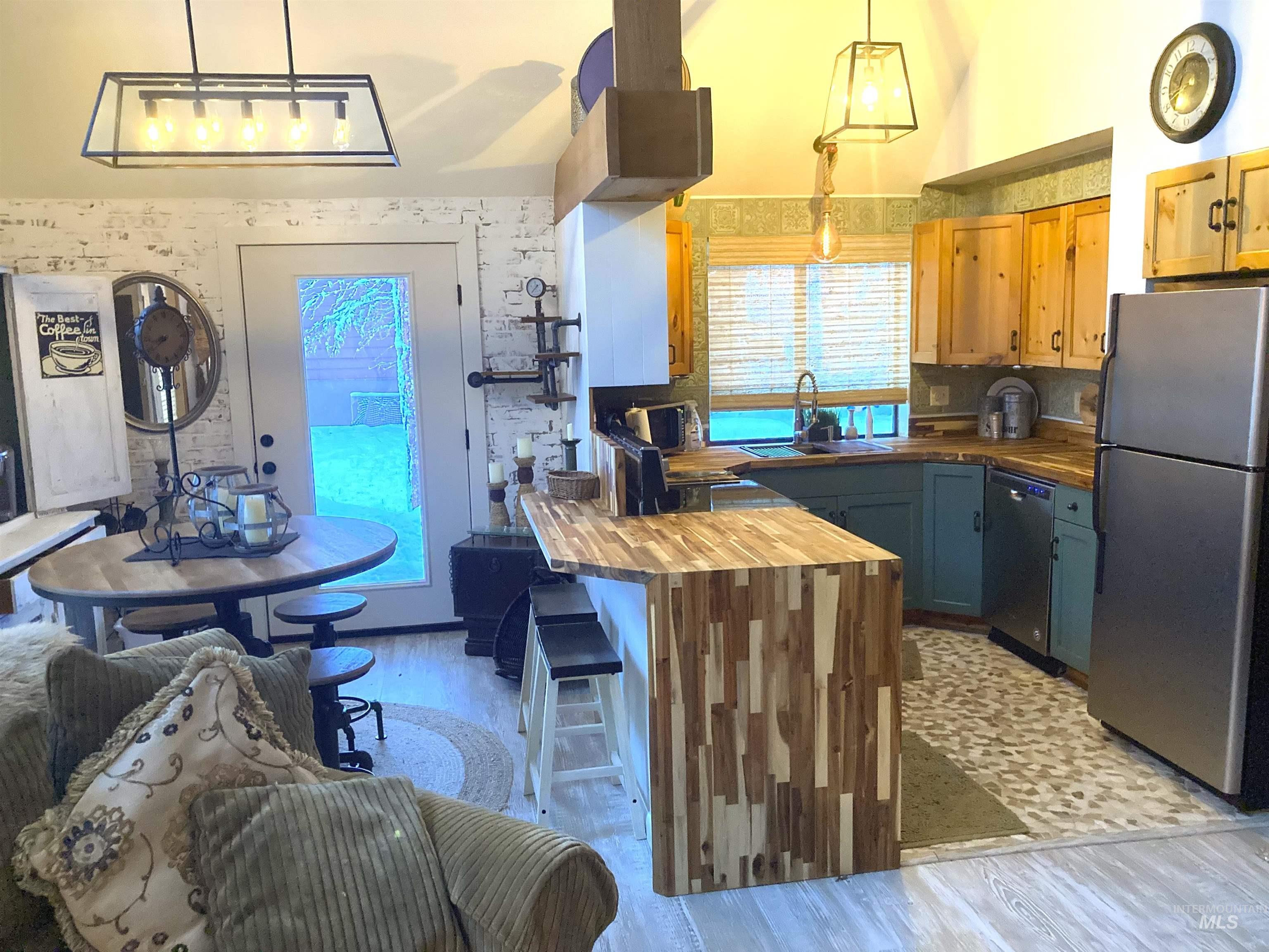 Kitchen with butcher block countertops, stainless steel appliances, a breakfast bar area, a peninsula, and light wood-style floors