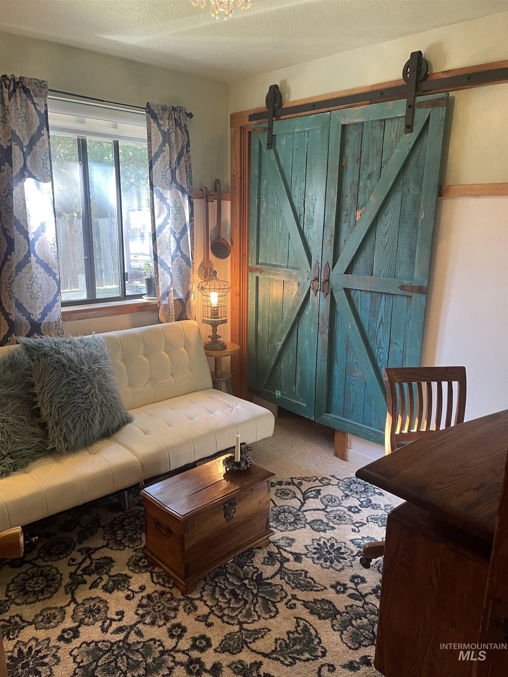 Living area with a textured ceiling, carpet flooring, and a barn door