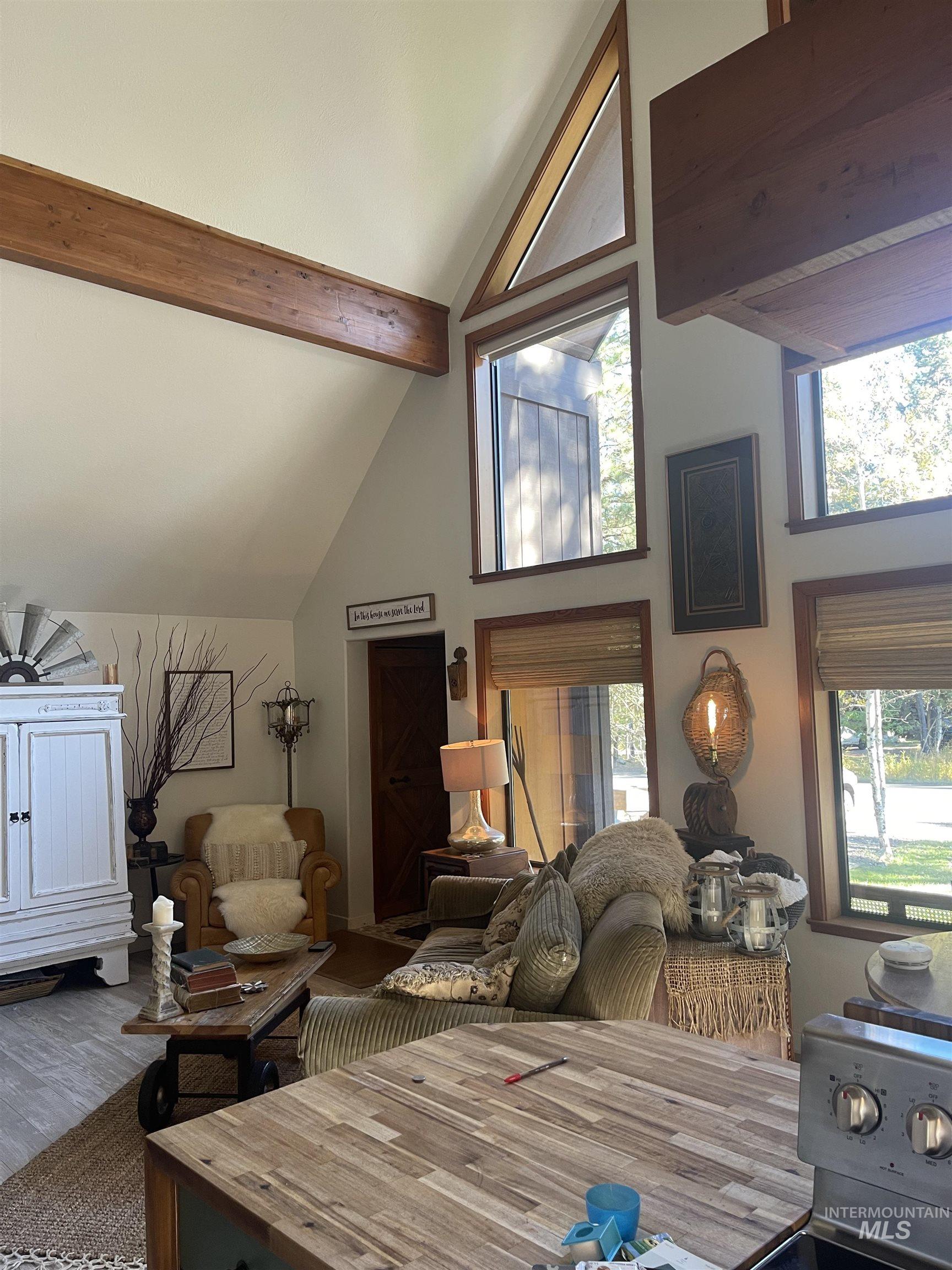 Living room with beamed ceiling, high vaulted ceiling, and wood finished floors