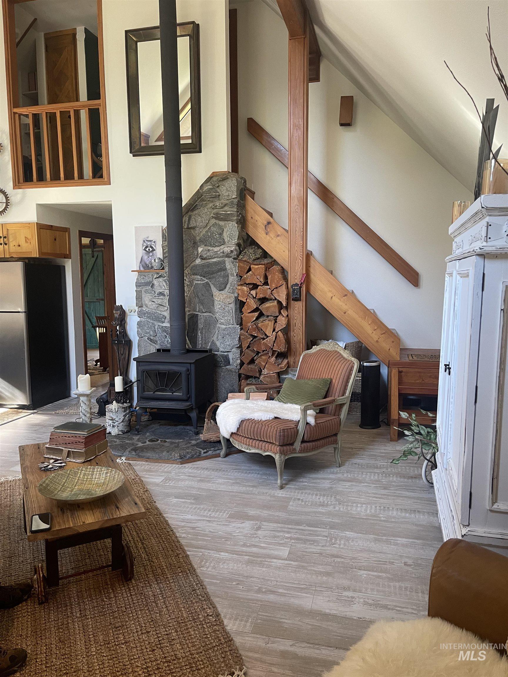 Living area with a wood stove, a high ceiling, and light wood-style flooring
