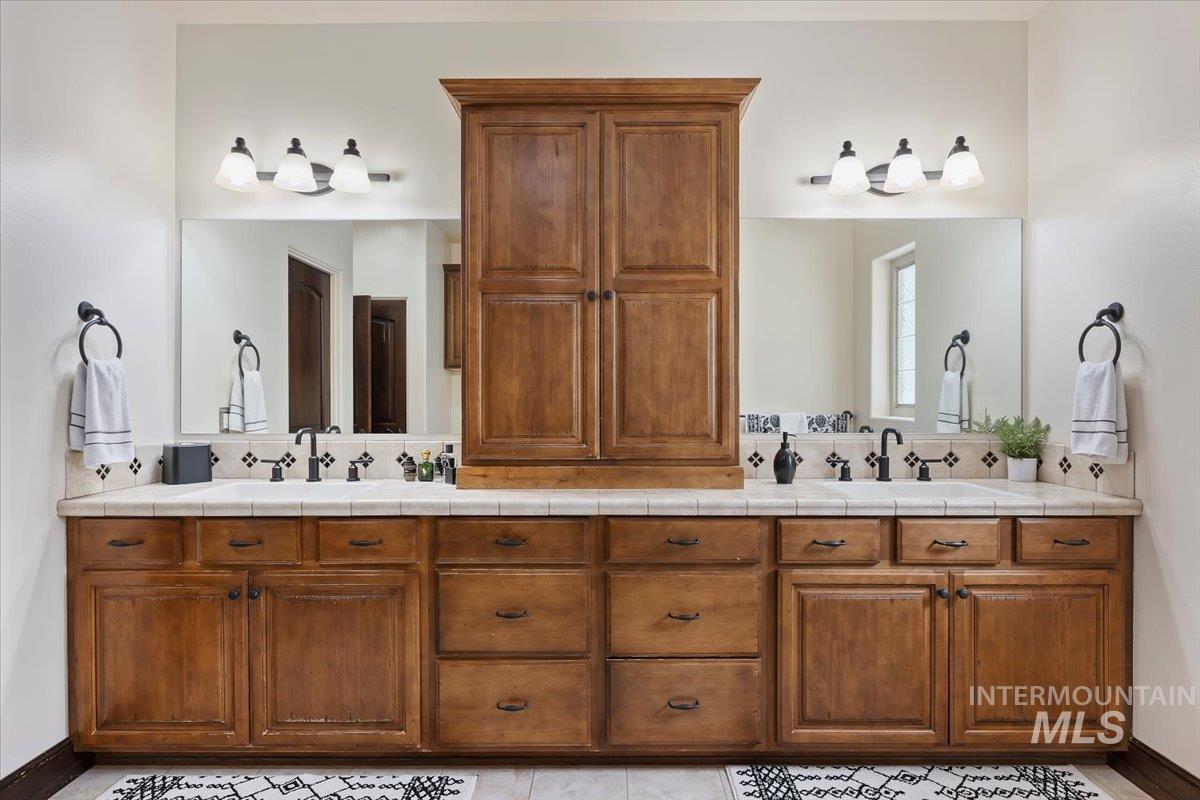 Full bath featuring double vanity and tasteful backsplash