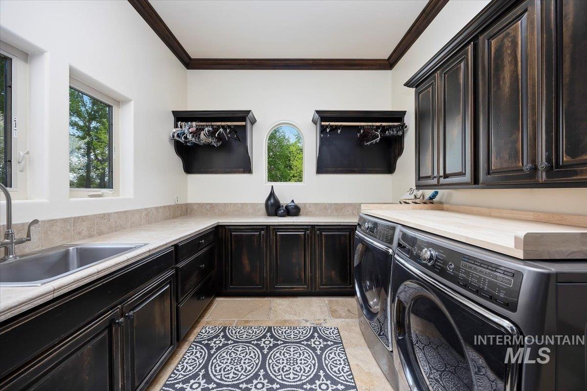 Laundry room featuring cabinet space, healthy amount of natural light, washing machine and clothes dryer, and crown molding