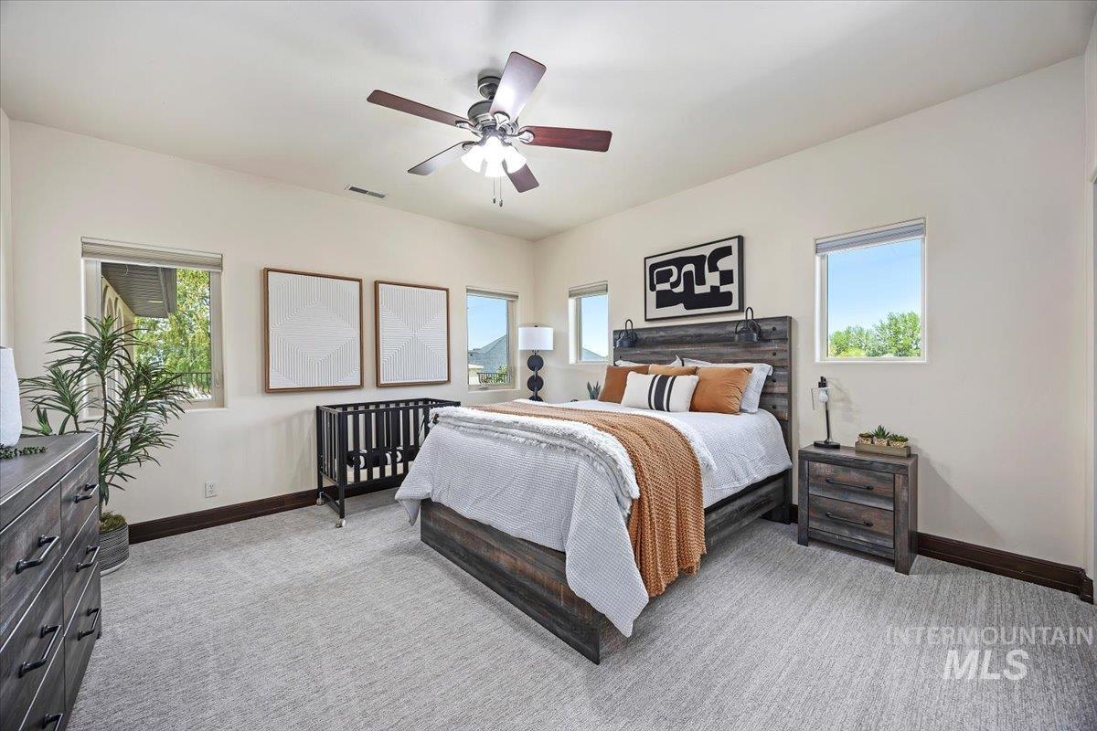 Bedroom featuring multiple windows, light carpet, and ceiling fan
