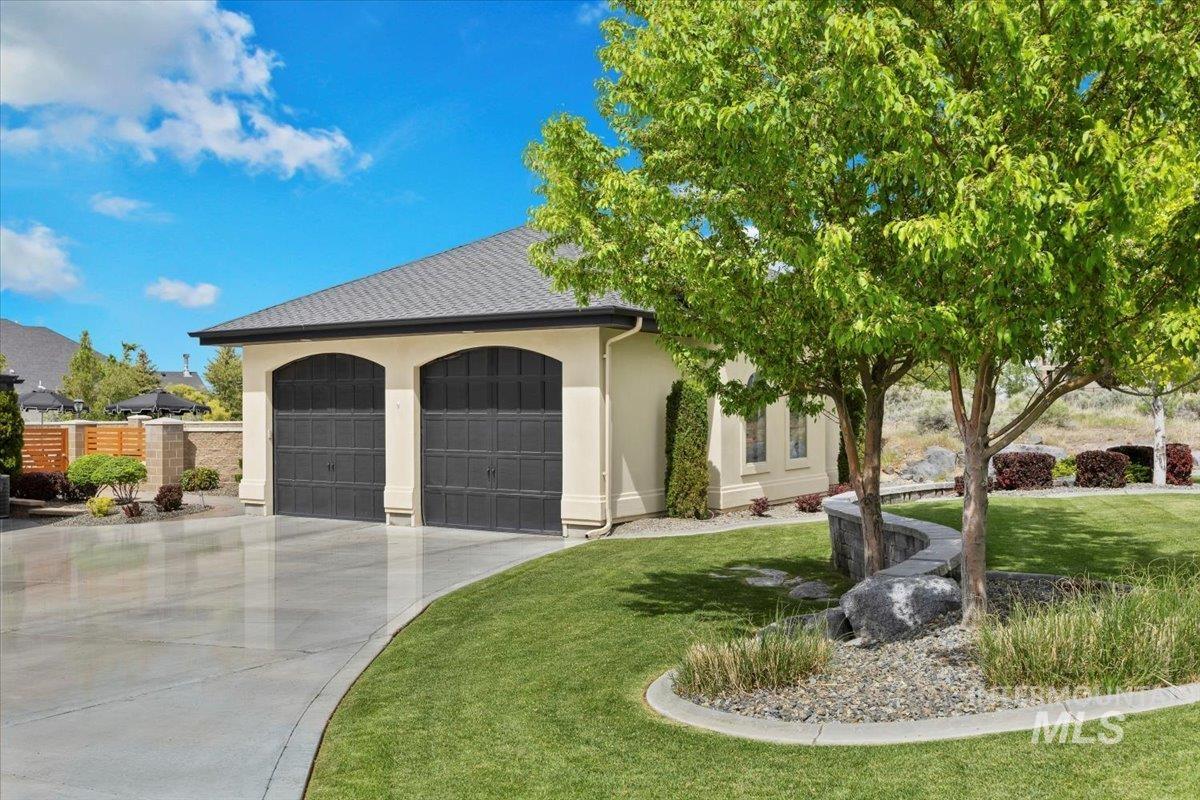 View of front facade featuring driveway, stucco siding, an attached garage, and roof with shingles