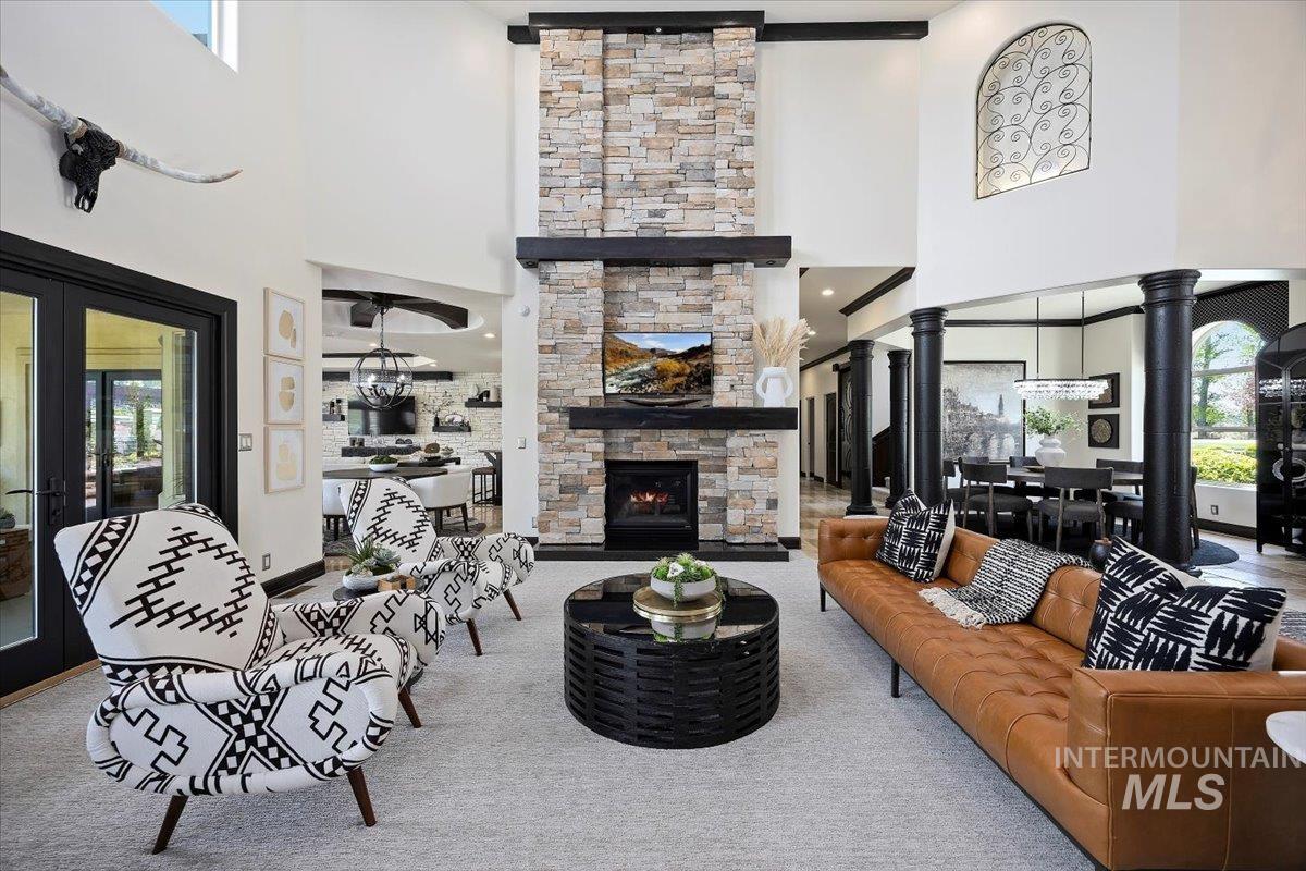 Living room with healthy amount of natural light, a fireplace, carpet flooring, and a towering ceiling