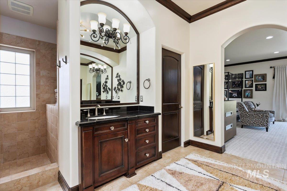 Bathroom featuring crown molding, vanity, a chandelier, a walk in shower, and recessed lighting