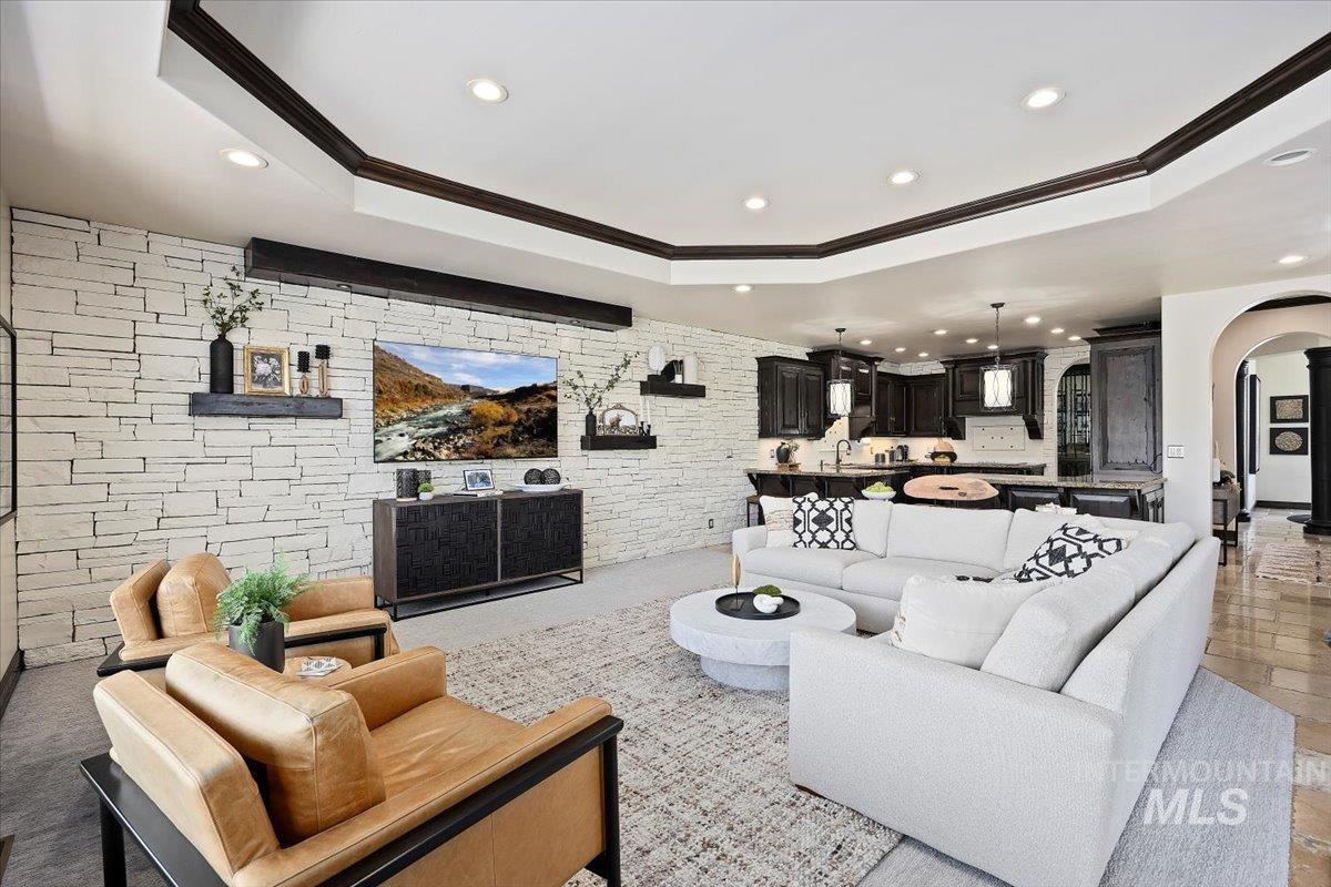 Living area with arched walkways, a tray ceiling, recessed lighting, and crown molding