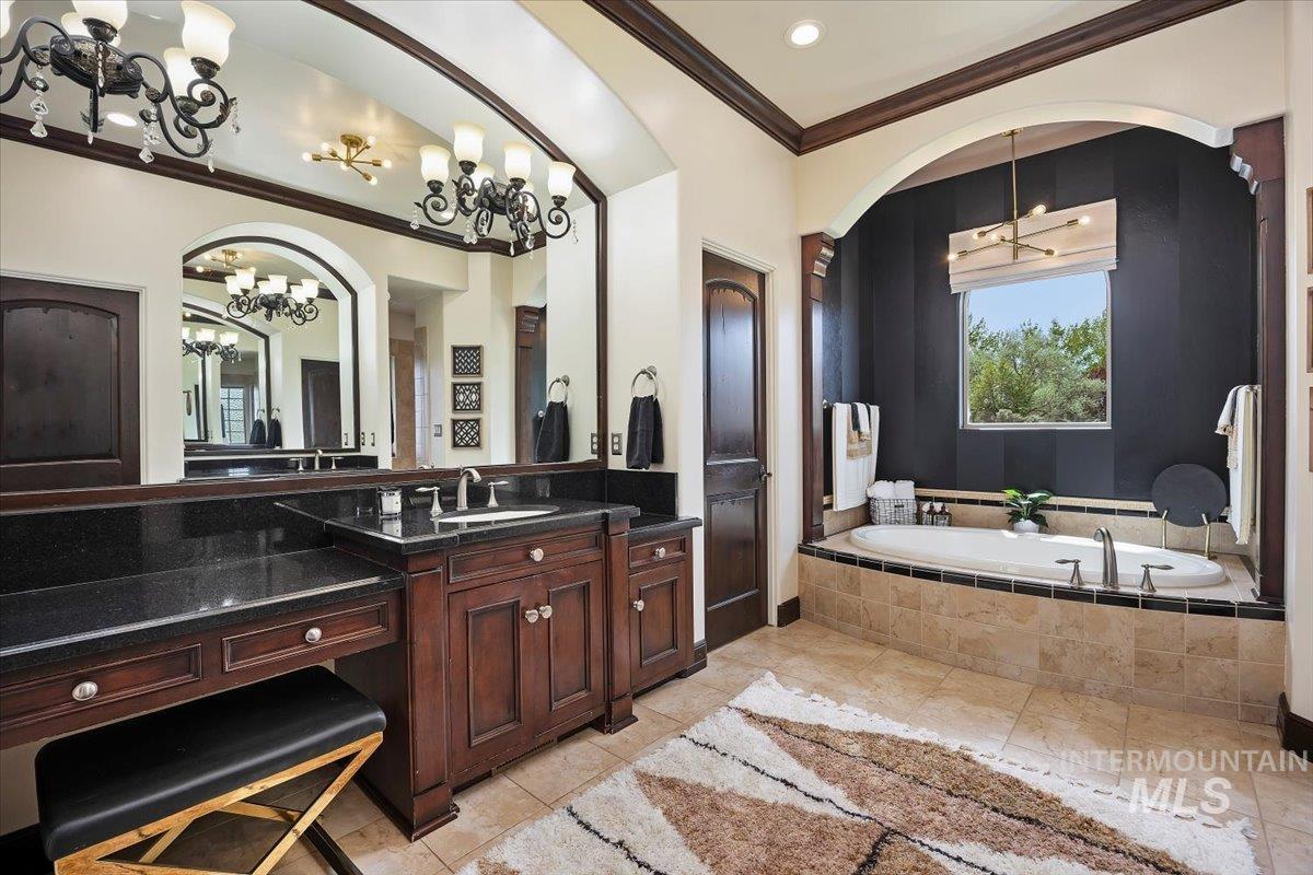 Full bath with a chandelier, crown molding, a bath, and vanity