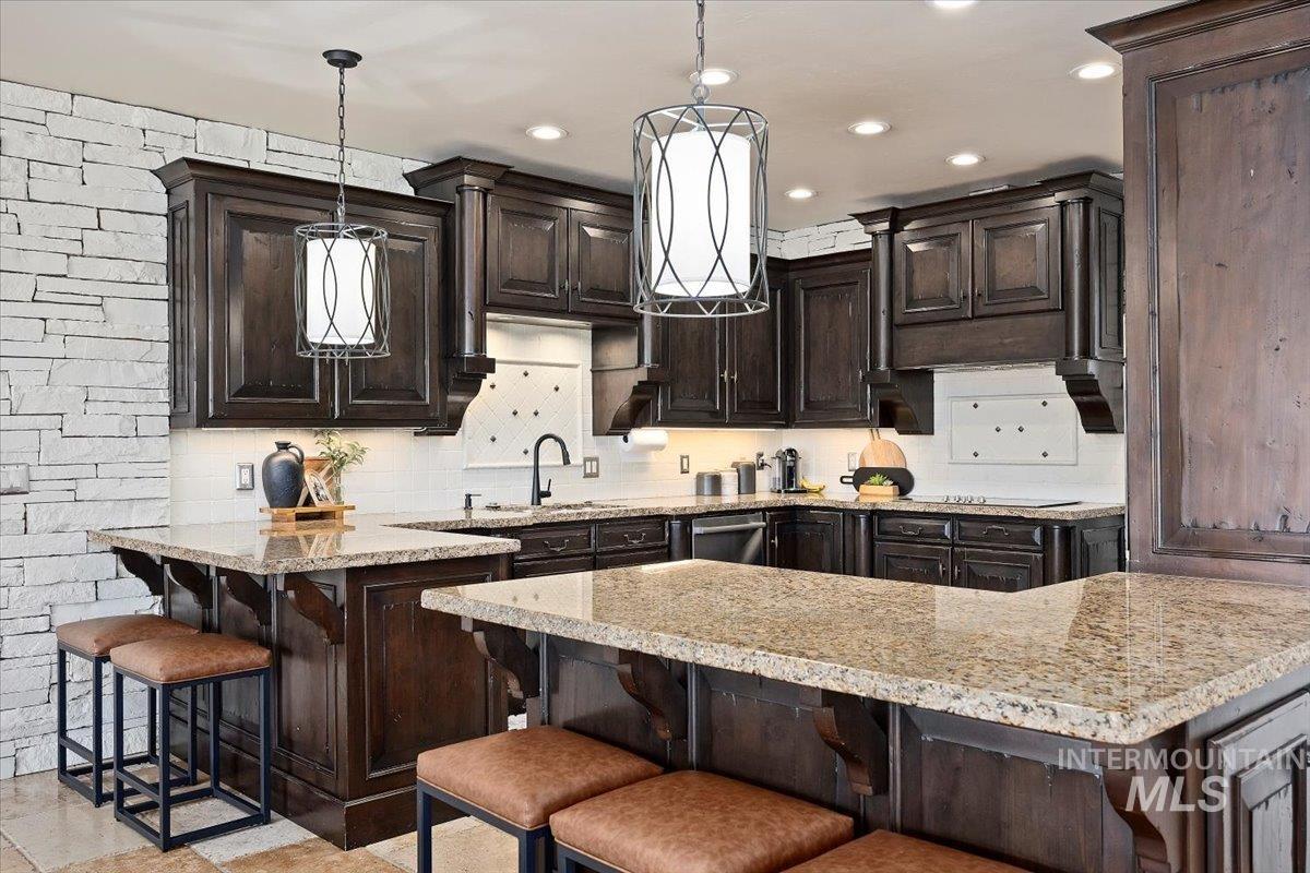 Kitchen featuring a breakfast bar, dark brown cabinetry, tasteful backsplash, light stone counters, and recessed lighting