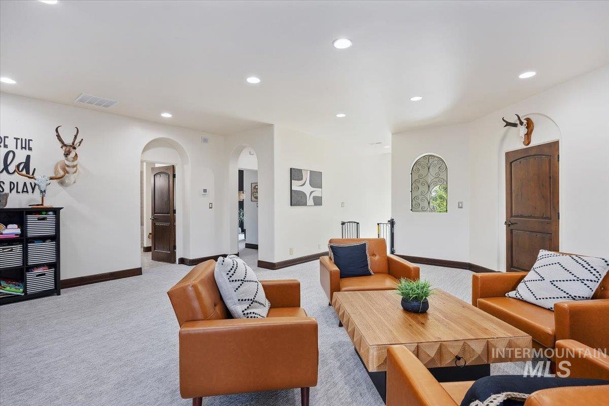 Living area featuring arched walkways, light colored carpet, and recessed lighting