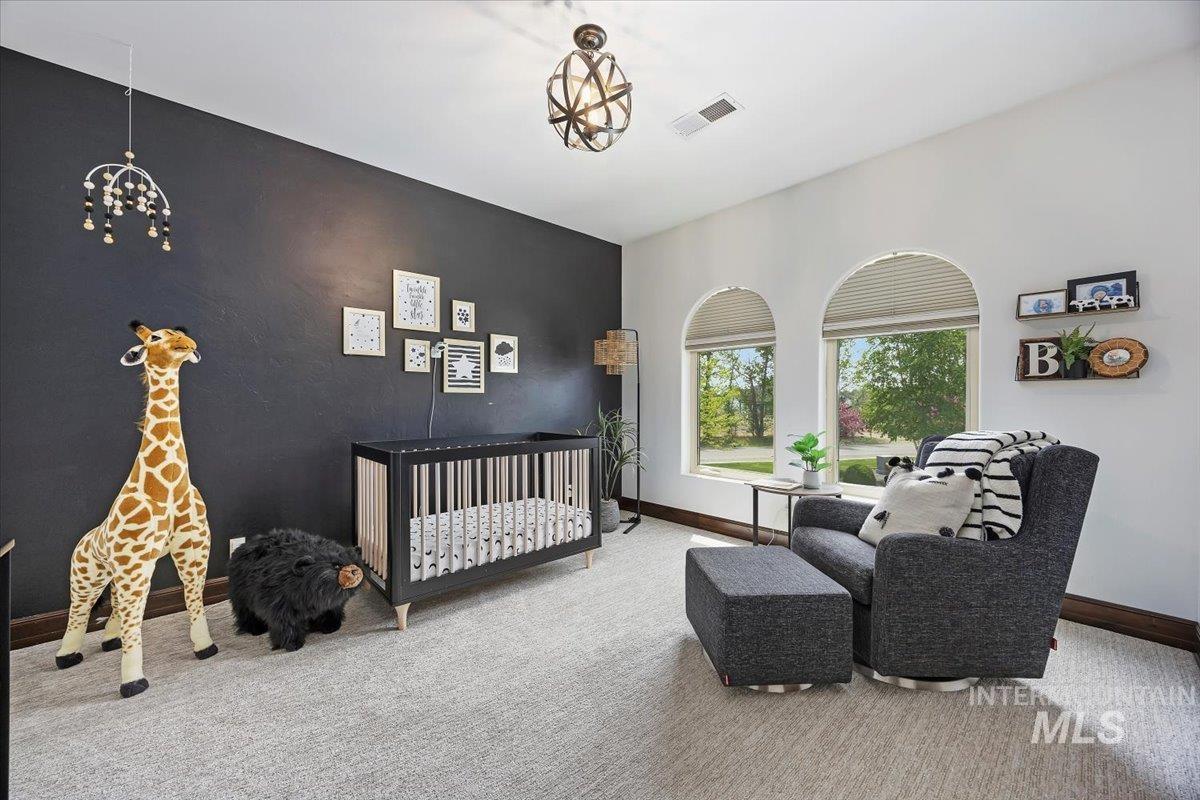 Bedroom featuring a chandelier, carpet, and a crib