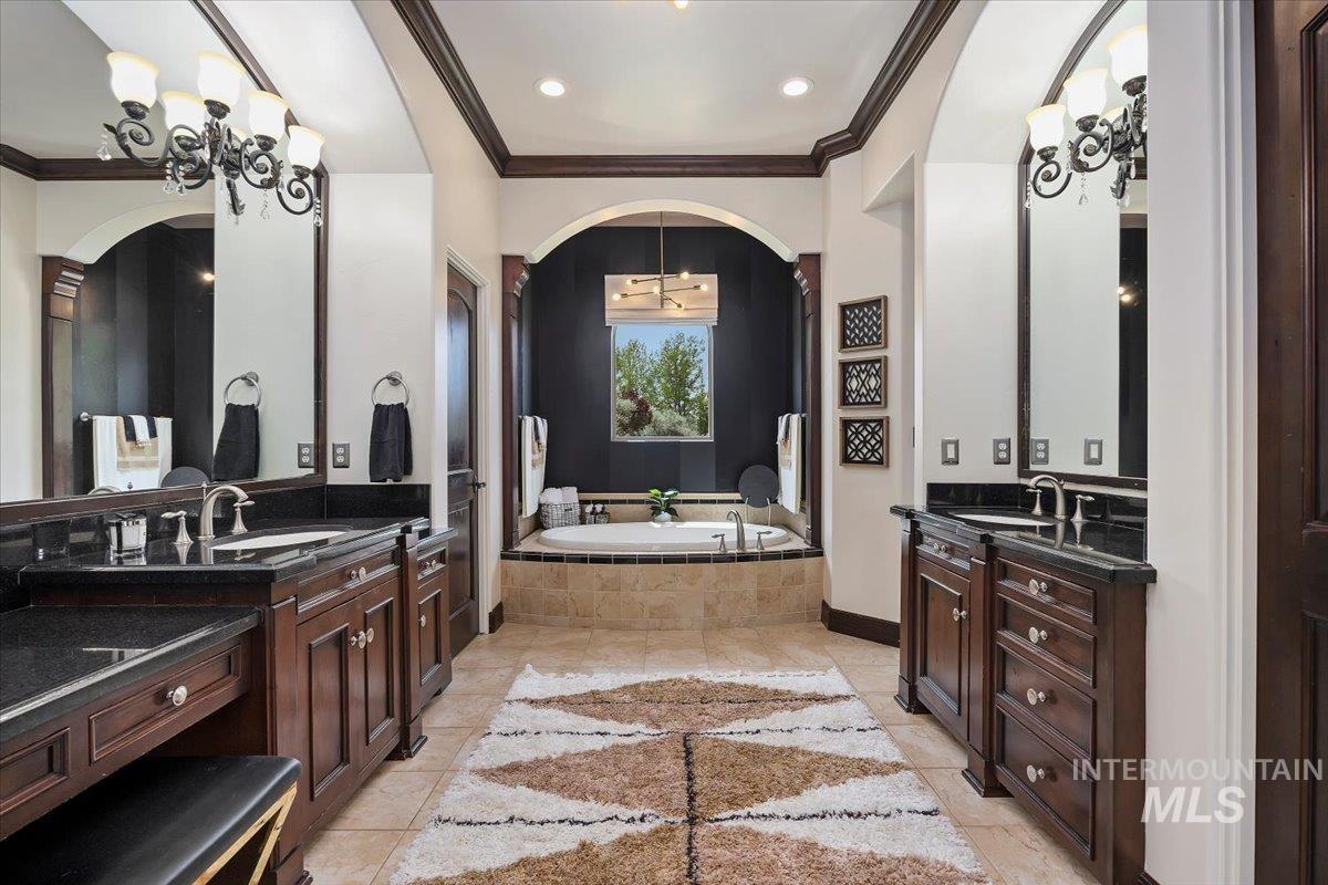 Bathroom with crown molding, a bath, two vanities, recessed lighting, and a chandelier