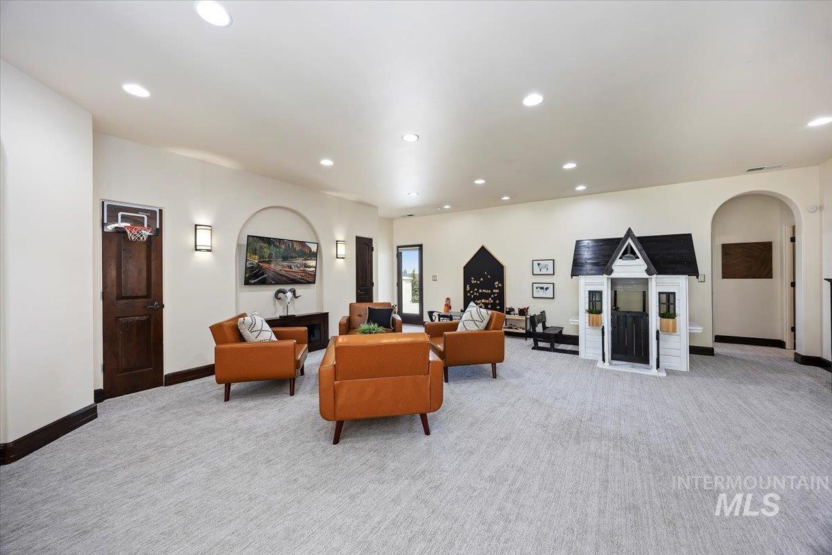 Living area featuring light colored carpet, recessed lighting, and arched walkways