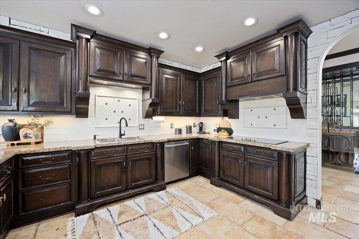 Kitchen featuring stone tile floors, backsplash, recessed lighting, dark brown cabinets, and dishwasher