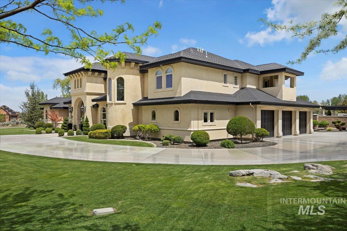 View of front of home featuring concrete driveway, stucco siding, a front lawn, and a garage