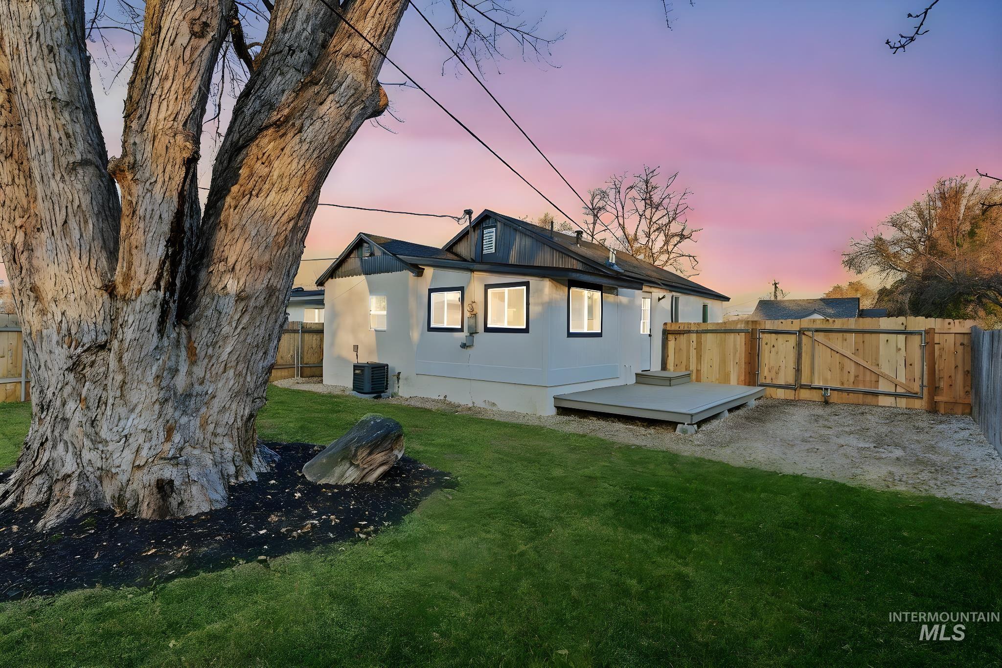 Back of house at dusk featuring a fenced backyard and a wooden deck