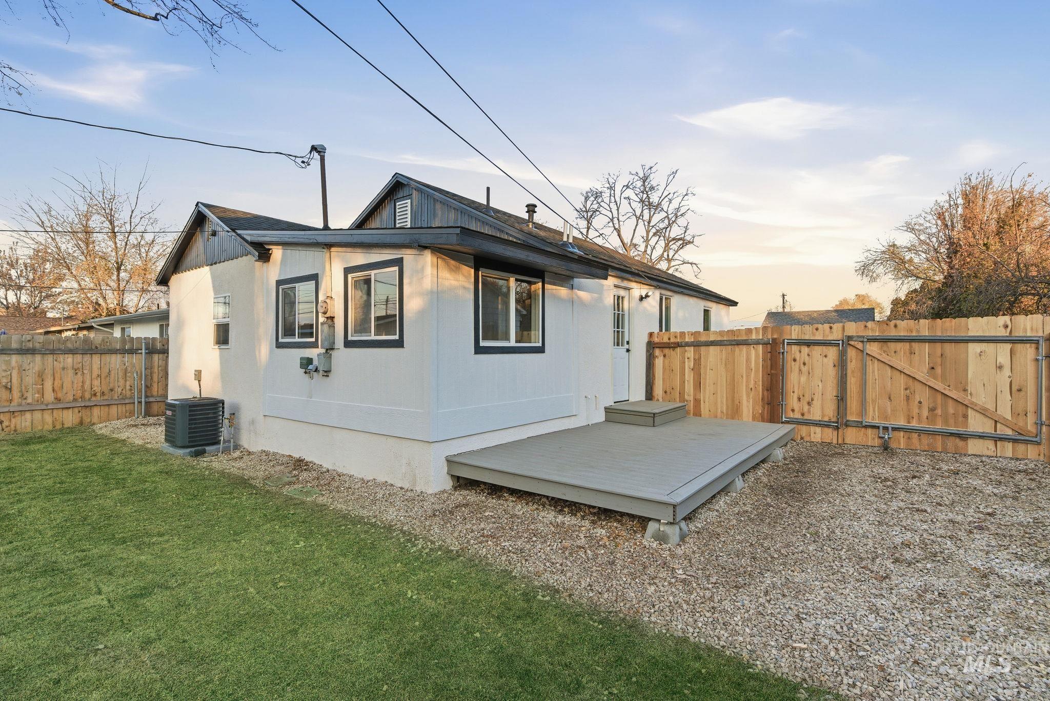 Rear view of property featuring a deck, a fenced backyard, and a gate