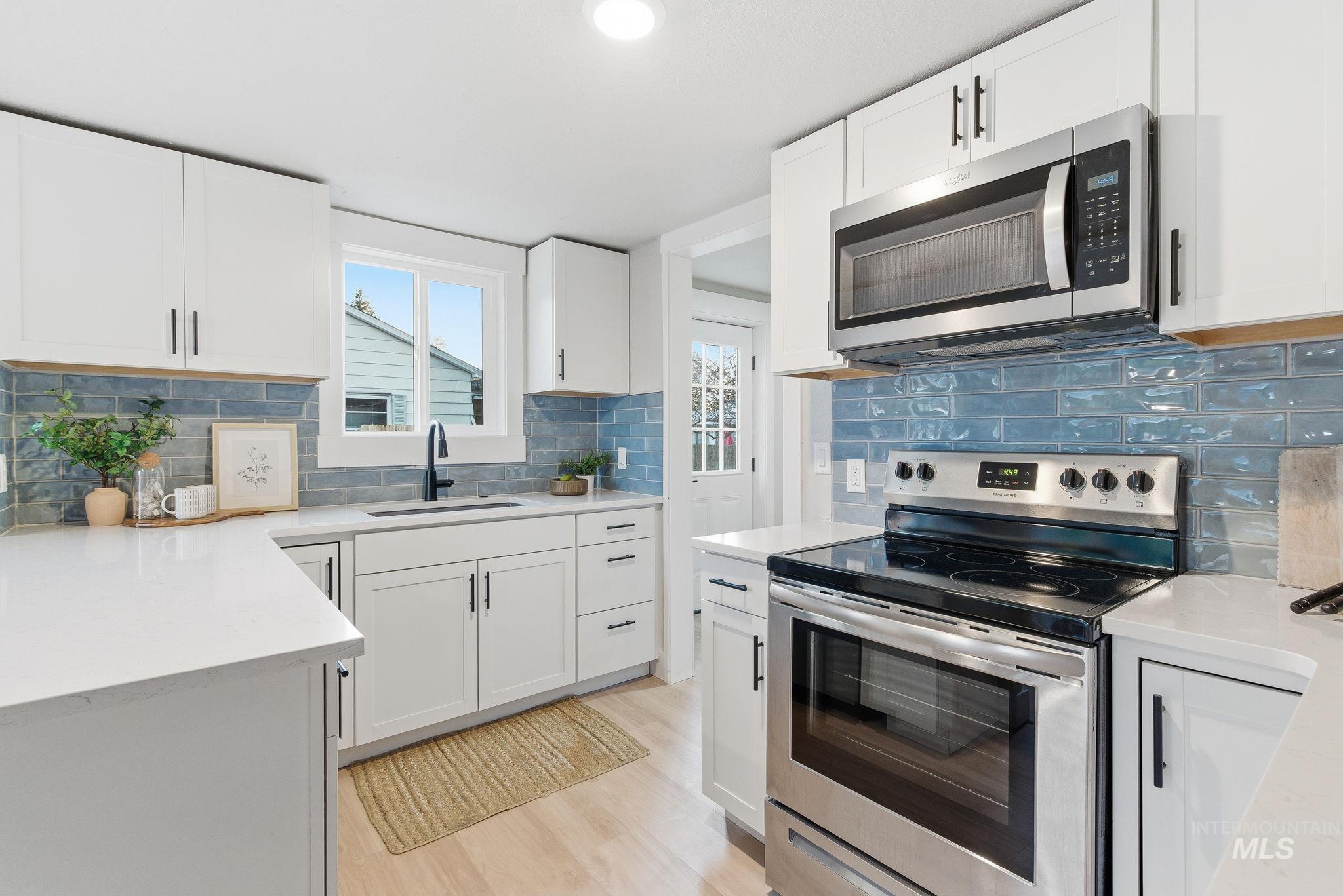 Kitchen featuring stainless steel appliances, white cabinetry, tasteful backsplash, light stone counters, and recessed lighting