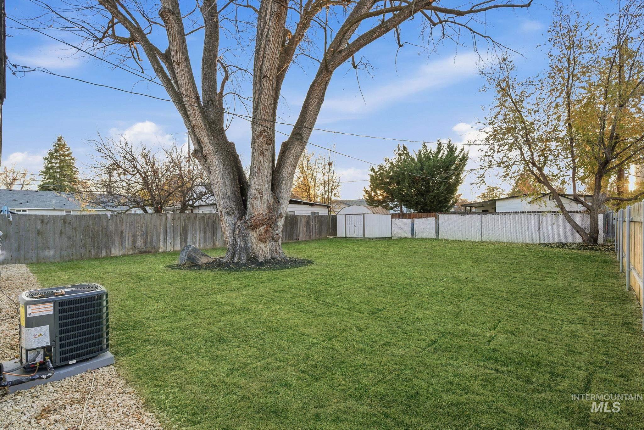 Fenced backyard featuring a storage unit