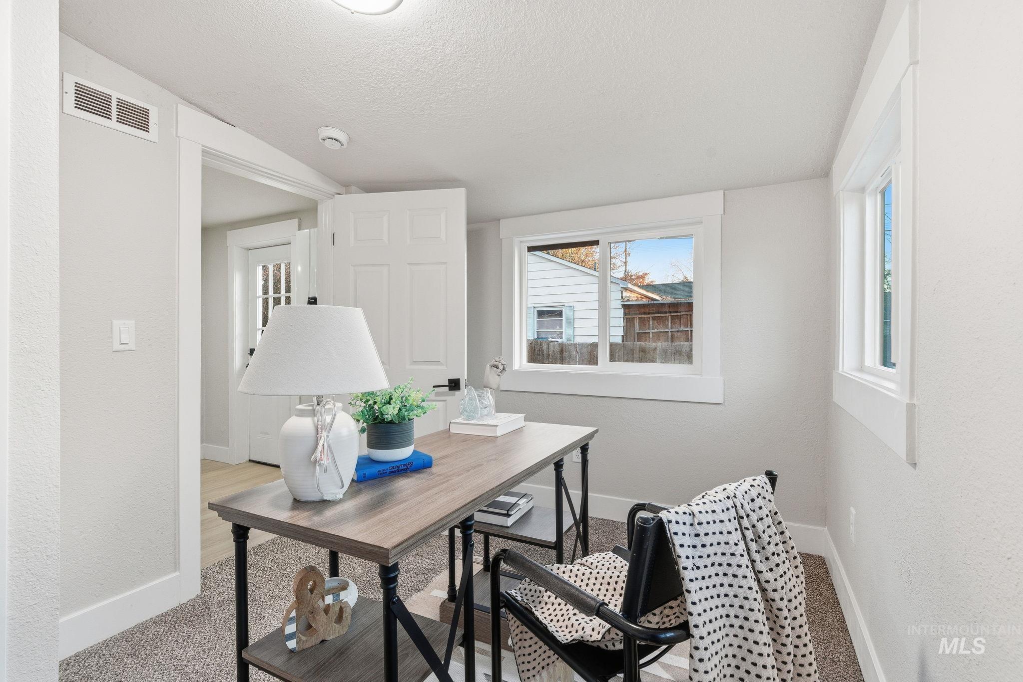 Carpeted home office with a textured wall and a textured ceiling