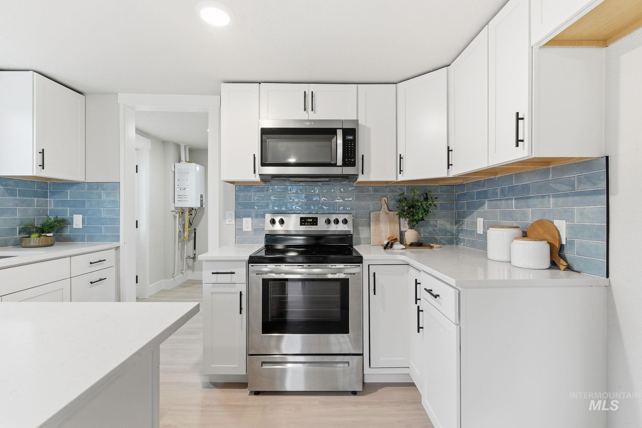 Kitchen with appliances with stainless steel finishes, white cabinets, decorative backsplash, and recessed lighting