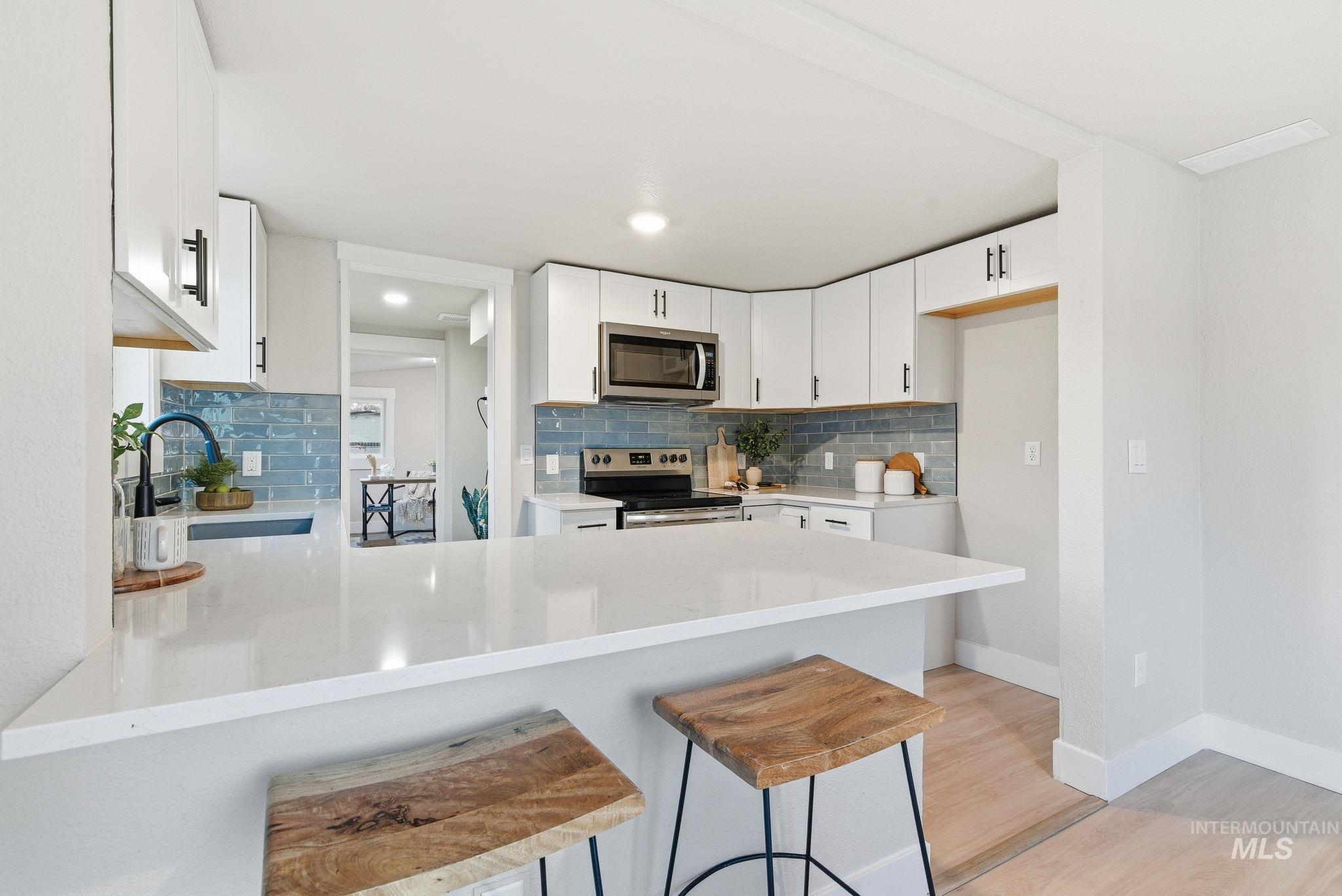 Kitchen featuring tasteful backsplash, a kitchen breakfast bar, a peninsula, light wood-type flooring, and recessed lighting