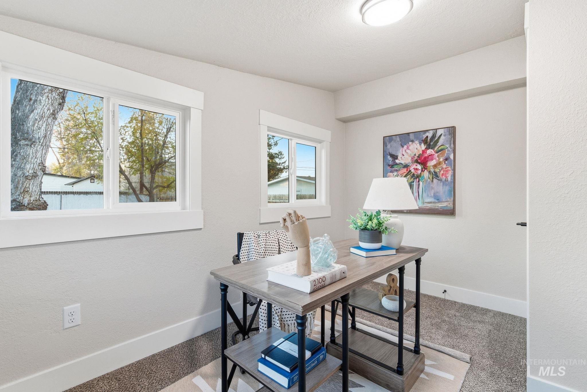 Home office featuring a textured wall and light colored carpet